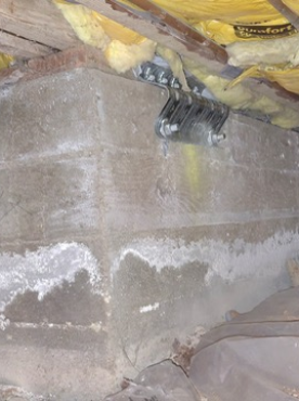 Worker installing plywood sheathing on a short wood cripple wall inside a San Diego raised-foundation crawlspace