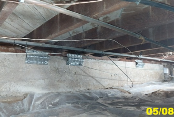 Technician inspecting short cripple wall framing inside a San Diego raised-foundation crawlspace